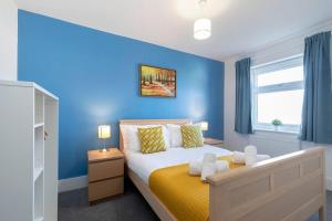 a bedroom with blue walls and a bed with yellow sheets at Modern & Spacious Home in Central Cheltenham in Gloucestershire
