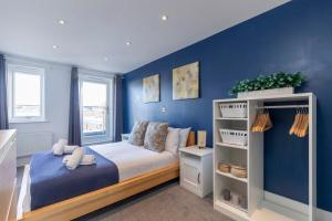 a bedroom with a bed with a blue wall at Modern & Spacious Home in Central Cheltenham in Gloucestershire