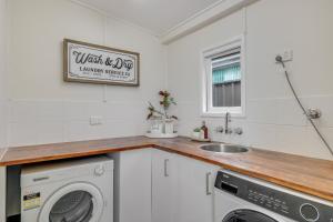 una cucina con lavatrice e lavandino di Bluewood Cottage - Cozy Charm, Steps from the City a Toowoomba
