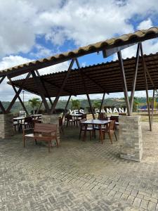 eine Gruppe von Tischen und Bänken unter einem Pavillon in der Unterkunft Casa para alugar em Bananeiras in Bananeiras