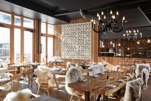 a restaurant with wooden tables and chairs and windows at Ecrin Blanc Resort Courchevel - Aquapark in Courchevel