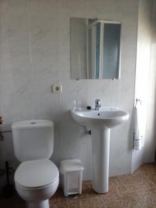 Baño blanco con aseo y lavamanos en Hostal Restaurante Parajes, en Castropol