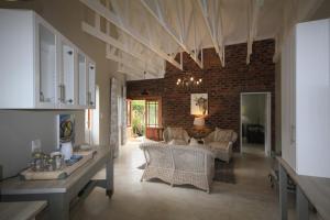 a living room with white furniture and a brick wall at Maryah House in Pretoria