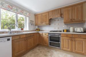 une cuisine avec des armoires en bois et un évier dans l'établissement Peaceful 3-Bed Cottage in Eastington, à Claypits