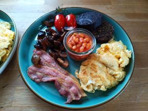 a plate of breakfast food with eggs bacon beans and tomatoes at Orkney Bed & Whisky in Orphir +3 photos