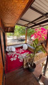 a porch with a red rug with pillows and a plant at Davi homestay in Sumbawa Besar +7 photos