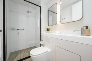 a white bathroom with a toilet and a sink at Luxe 3BR Skyline Sunset Residence Level 63 - CBD Views, Parking, Pool, Sauna, Gym in Melbourne +26 photos