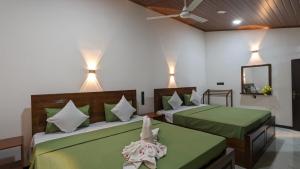 a bedroom with two beds with green sheets and a mirror at MPS Paradise villa in Tangalle