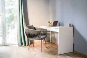 a desk with a laptop and a chair next to a window at Boutique Hotel Aviator in Belgrade