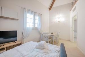 a white room with a bed and a table and a television at Ca' Serena - Murano centro - 10 min from Venice in Venice