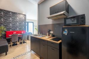 a kitchen with a black refrigerator and a dining room at Angoulême, cosy T2 centre ville , TV , WIFI , 4 pers , moderne , parking in Angoulême