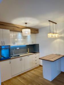 una cocina con armarios blancos, fregadero y 2 luces en VIP House 4, en Vrnjačka Banja