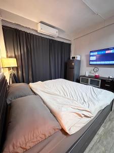 a bedroom with a bed and a tv in a room at Mango Rooms & Rooftop in Bangkok