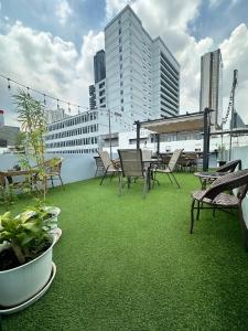 a balcony with chairs and tables and green grass at Mango Rooms & Rooftop in Bangkok