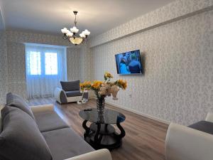 Una sala de estar con un sofá y una mesa con flores. en Luxury Sea View apartment by Bakuapart, en Baku