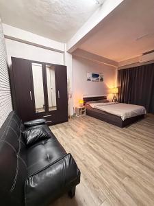 a hotel room with a bed and a leather couch at Mango Rooms & Rooftop in Bangkok +2 photos