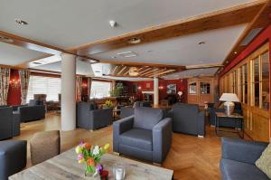 eine Lobby mit Sofas, Tischen und Stühlen in der Unterkunft Silvretta Parkhotel in Klosters
