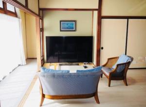 a living room with a large tv and a couch and chairs at 福のや in Unnan