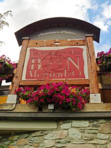 a sign on the side of a building with flowers at La Maison Du Bon Megnadzo in Doues