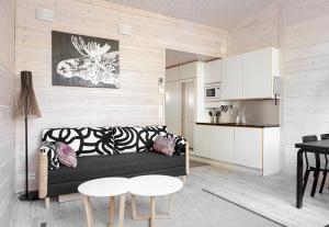 a living room with a black couch and a kitchen at Pyhä Igloos in Pyhätunturi