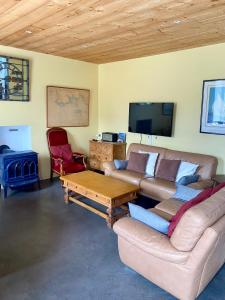 a living room with a couch and a table and a tv at Maison typique du pays bigouden in Tréffiagat