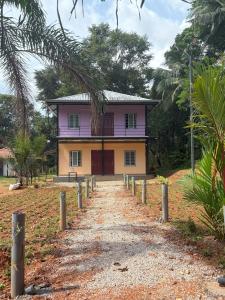 a pink house with a dirt road in front of it at Lead Farm Stay in Palakkad +8 photos