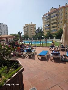 a group of people sitting in lounge chairs by a pool at vacation720 in Benalmádena