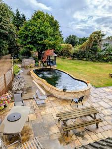 una piscina in un cortile con panchine e tavoli di Self-contained 2 bedroom annexe in secluded country house a Uppingham