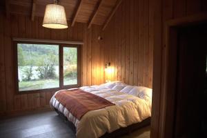 a bedroom with a bed with a window in it at Casa en Lago Hermoso sobre Laguna Cristalina con Muelle Privado in San Martín de los Andes