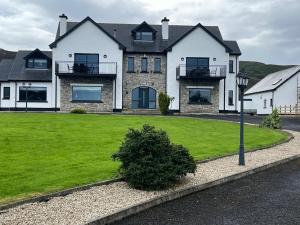 a large house with a green lawn in front of it at Ocean Breeze in Dunfanaghy
