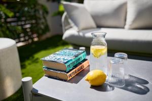ハベアにあるLuxury apartment Tamana Garden - by Welcomelyの本と花瓶と水の入ったグラスとレモンが置かれたテーブル