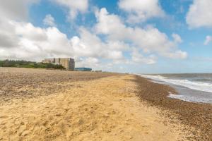 a sandy beach with a building in the background at The Avocet in Sizewell