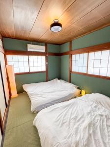 two beds in the corner of a room with windows at Totono Amami in Karitachō