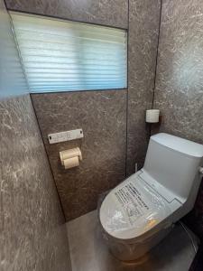 a bathroom with a toilet with a mirror and a window at Totono Amami in Karitachō +20 photos
