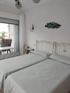 a white bedroom with two beds and a window at Primera línea in Castro-Urdiales