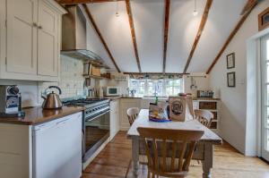 een keuken met witte kasten en een tafel met stoelen bij Dressmakers Cottage in Wrentham