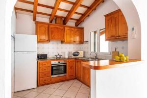 a kitchen with wooden cabinets and a white refrigerator at Villa Maru II by Villa Plus in Cala en Porter