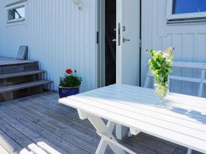 a white picnic table with a vase of flowers on a porch at 4 person holiday home in Økerø in Öckerö