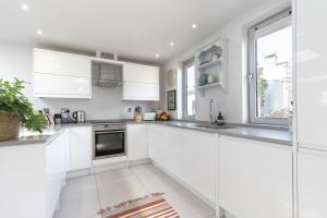 a white kitchen with white cabinets and a window at Contemporary 2-Bed 2-Bath Home with Parking in Cheltenham