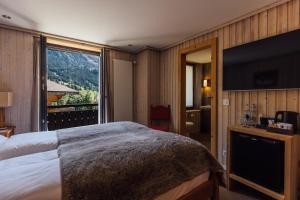 een hotelkamer met een bed en een groot raam bij Hotel Sanetsch in Gsteig