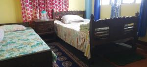 a bedroom with two twin beds and a dresser at Mountain Valley Home Stay in Darjeeling
