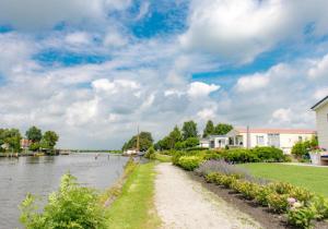 a path next to a river with a house at Chalet Meerwijck mit Terrasse am Wasser und Meer mit Schwimmbad in Kropswolde