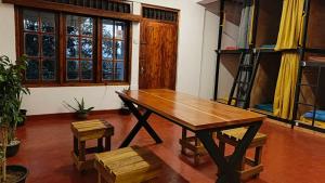 a wooden table and stool in a room with windows at Carls' Corner in Kandy
