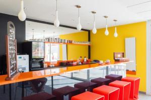 a restaurant with a bar with red stools and yellow walls at Villa F2 piscine et jardin - Saint-Cyprien in Saint-Cyprien