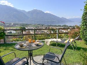 a patio with a table and chairs and a view of the mountains at Casa Ramarro by Fewotessin in Gordola