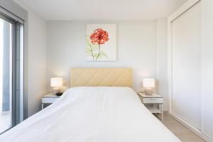 a white bedroom with a bed and two lamps at La Tejita, comfortable one-bedroom apartment in El Médano +18 photos