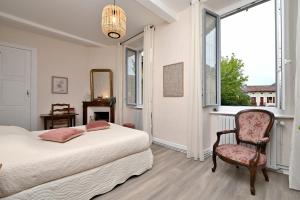 Un dormitorio con una cama y una silla y una ventana. en Maison L'Arénoulat, en Aspet