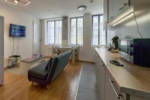 a room with a kitchen with a couch and a microwave at Séjour tout confort en plein coeur de Nevers, studios Galet-Carbone ou Terra Cotta in Nevers