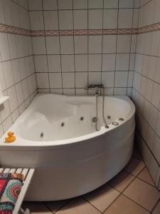 a white tub in a bathroom with a tiled wall at Dejligt og stort hus med spa og sauna in Roslev