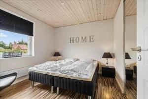a bedroom with a bed with a home sign on the wall at 0301-Romo-Langdalsvej-11 in Vesterhede
